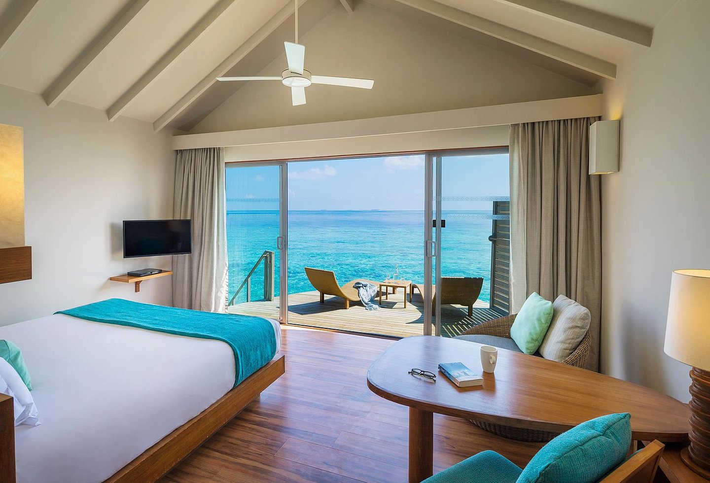 Zimmer im Centara Ras Fushi Resort & Spa mit Terrasse und Blick auf das türkisblaue Meer.