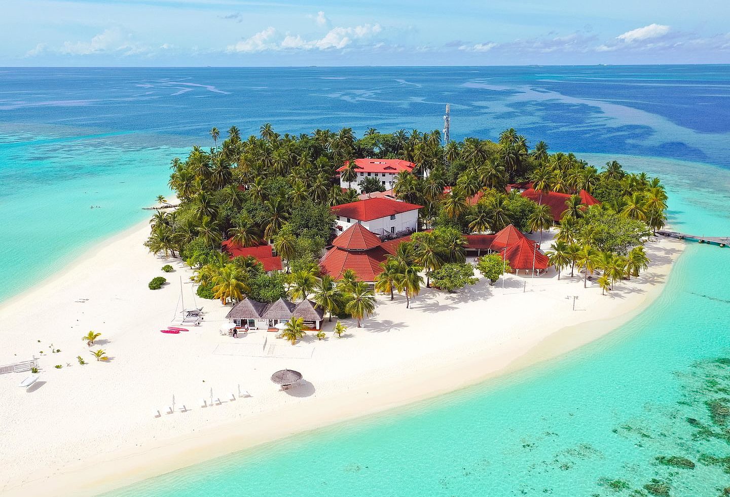 Blick auf eine tropische Insel, mit Hotelanlage umgeben von Palmen.