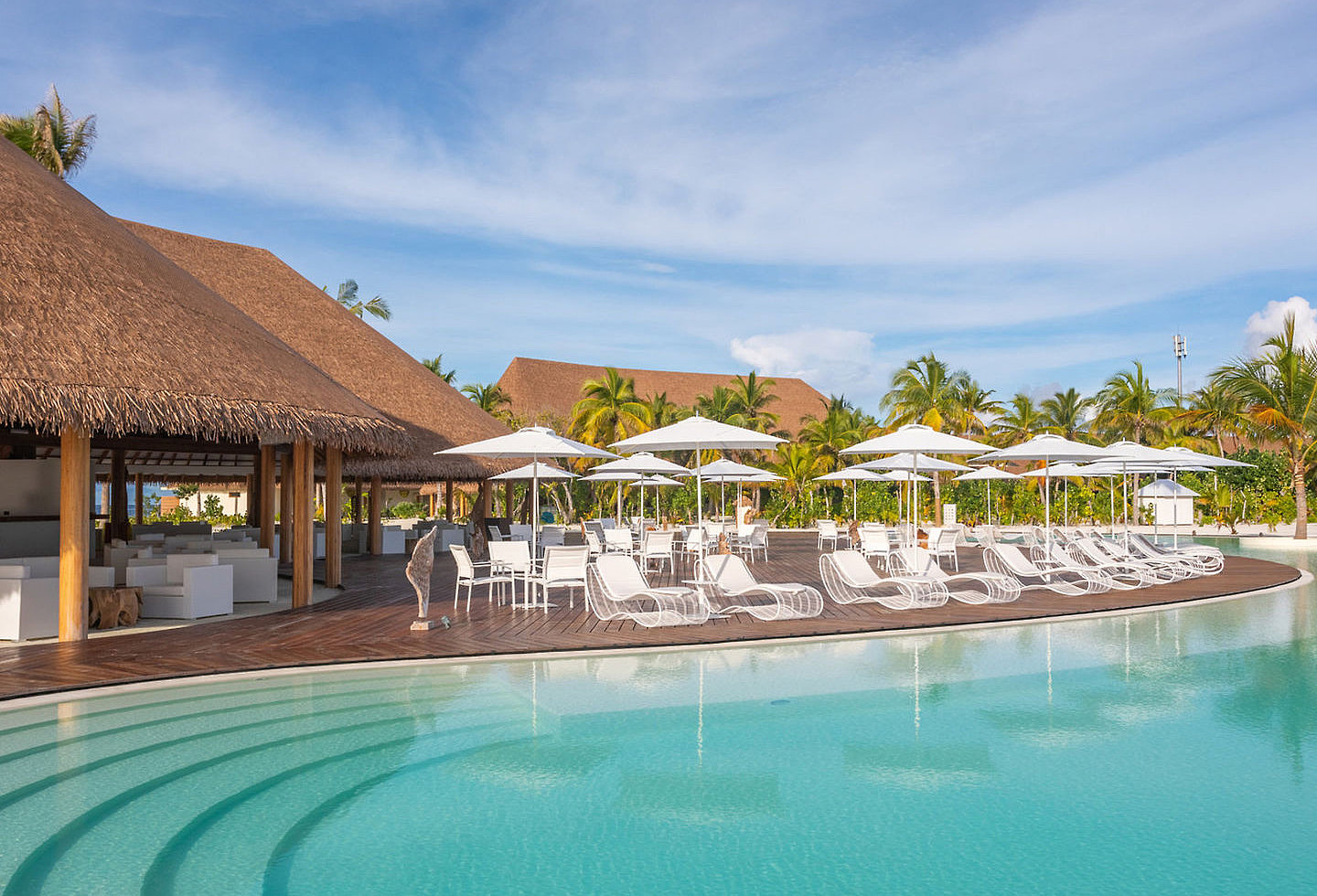 Malediven Cinnamon Velifushi Große Poolanlage mit weißen Sonnenliegen und Schirmen auf den Malediven.