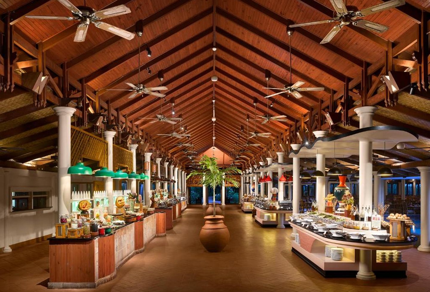 Offenes Restaurant mit hohem Holzdach, Buffetstation und großzügigem Sitzbereich.