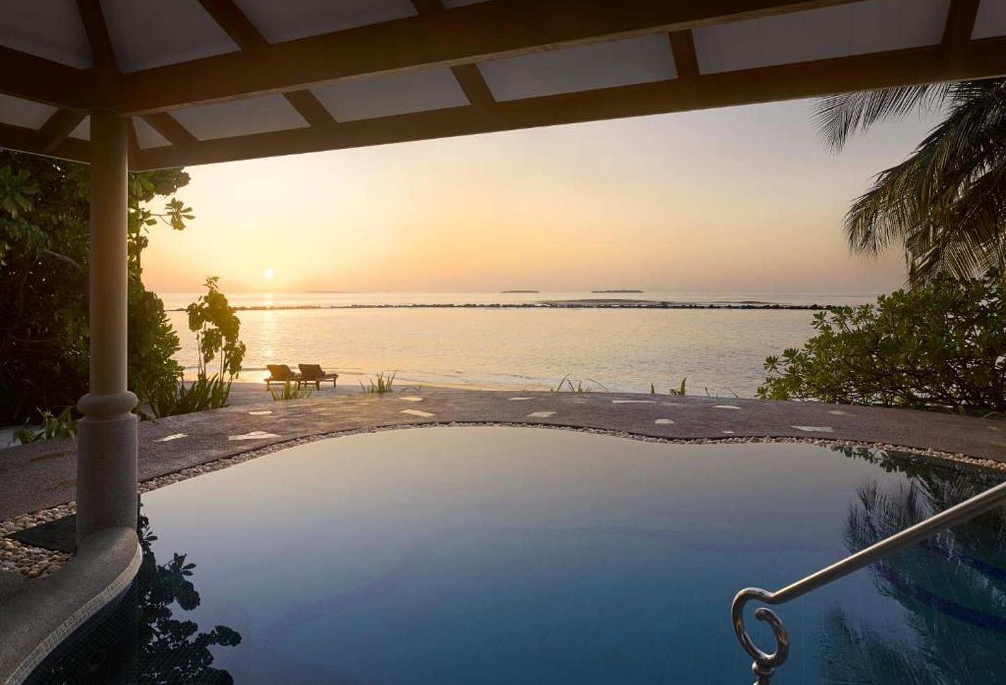 Infinity-Pool mit Meerblick und Sonnenuntergang unter überdachter Terrasse.