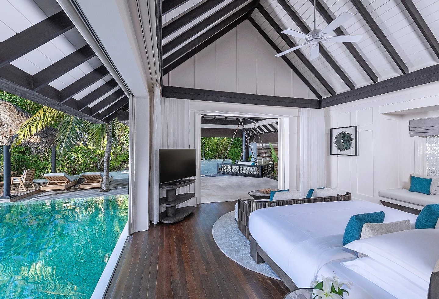 Helles Schlafzimmer mit Doppelbett, Poolzugang und Blick ins tropische Grün.