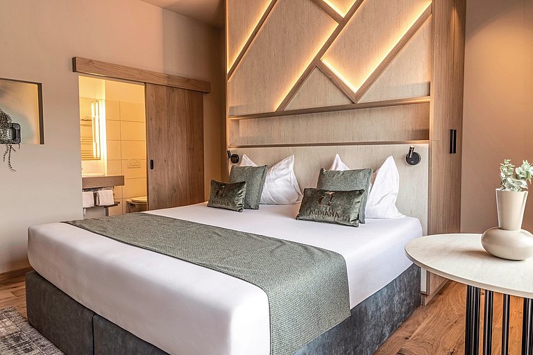 Blick in ein Hotelzimmer mit Doppelbett, moderner Architektur und Badezimmer.