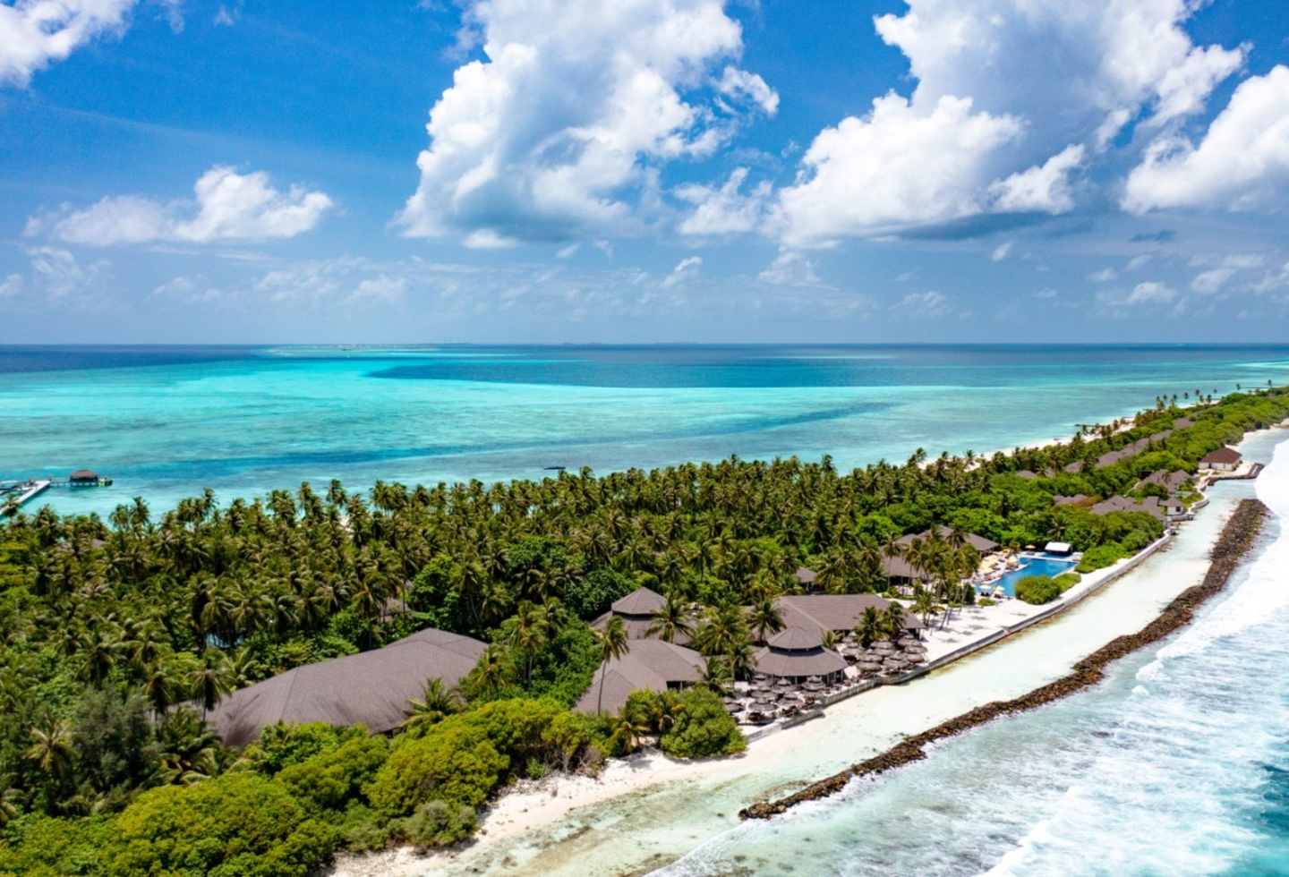 Luftaufnahme einer tropischen Insel mit Sandstrand, Palmen und türkisblauem Meer.