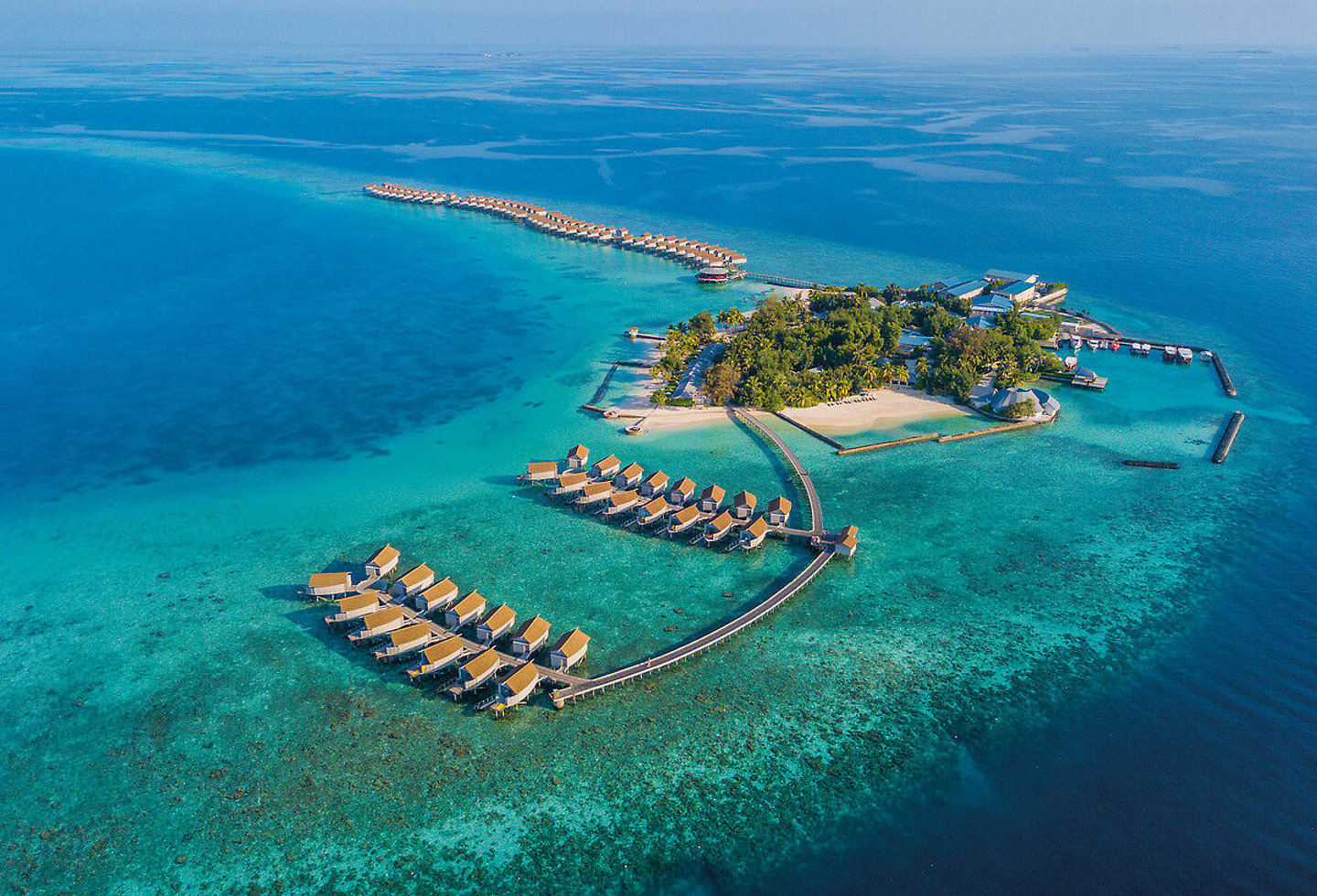 Blick auf eine kleine Insel mit Wasser Villen, tropischem Grün und Sandstrand.