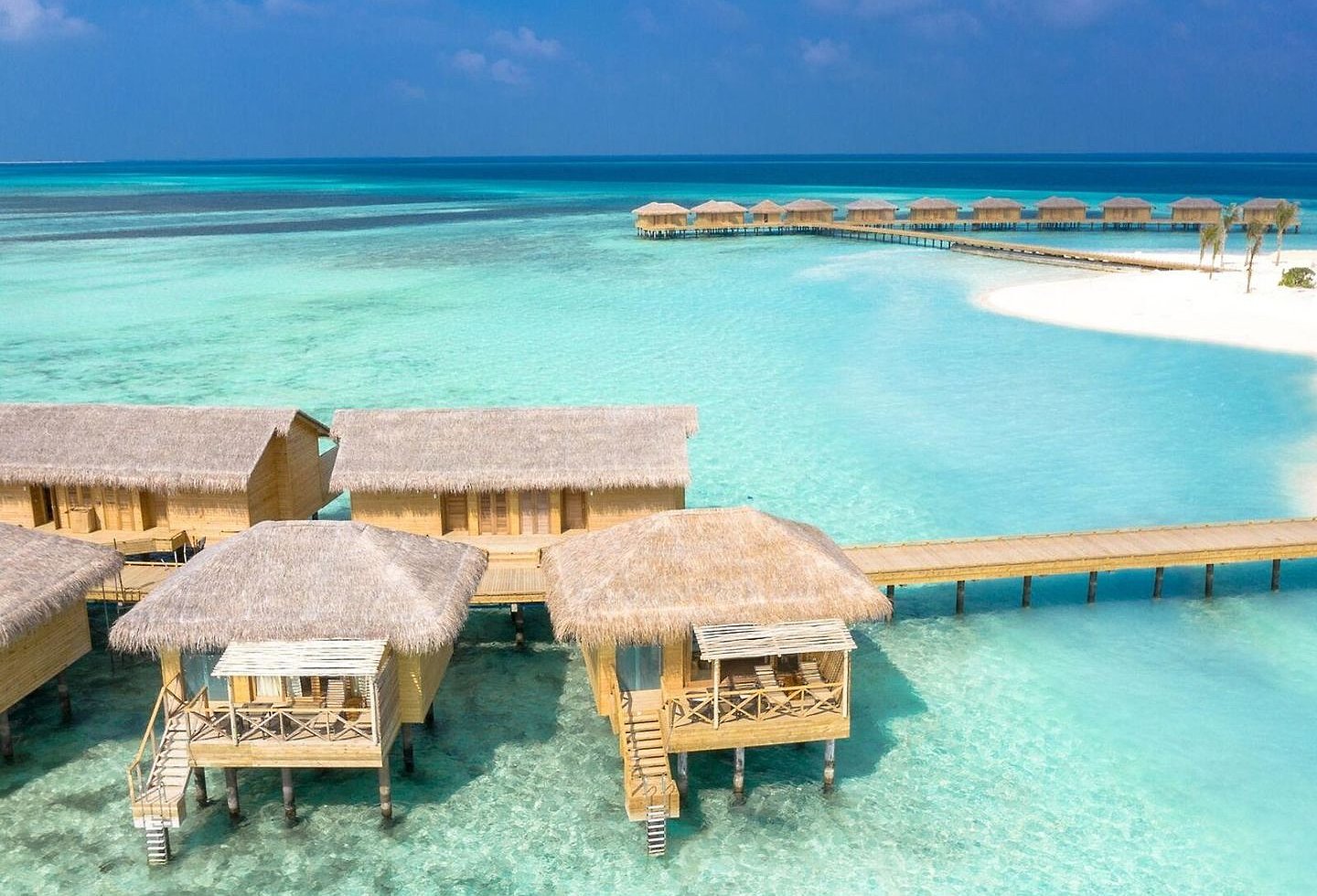 Luftaufnahme des Resorts mit Villen und türkisfarbenem Wasser.