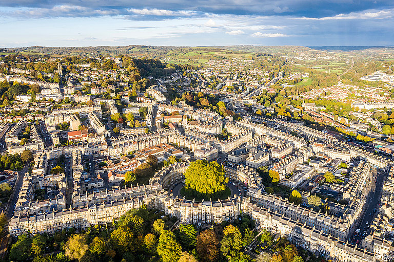 Luftaufnahme einer historischen Stadt mit Kirchtürmen, Straßen und grünen Bäumen.