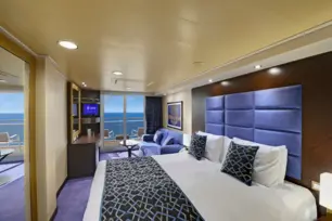 Moderne Balkonkabine mit Doppelbett, Spiegel, Couch, blauen Akzenten und Meerblick.