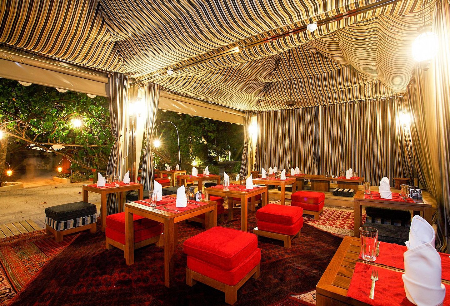 Offenes Restaurant am Abend, mit heller Beleuchtung, roten Hockern und schöner Aussicht.