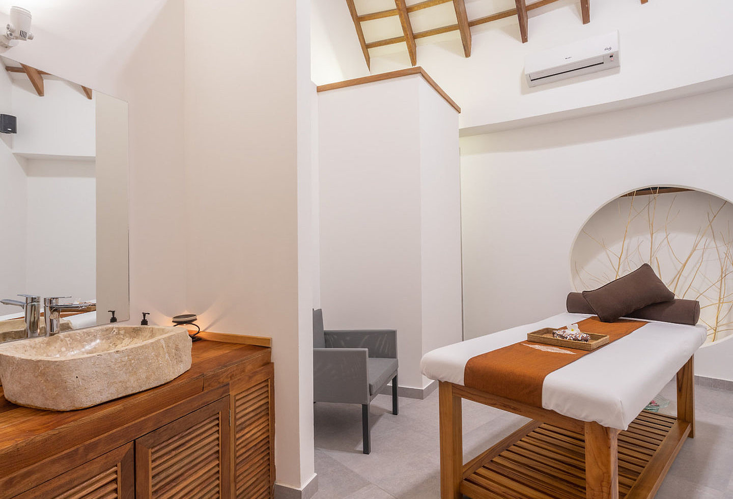 Massagebereich mit weißer Fassade, gemütlicher Liege und Waschbecken.