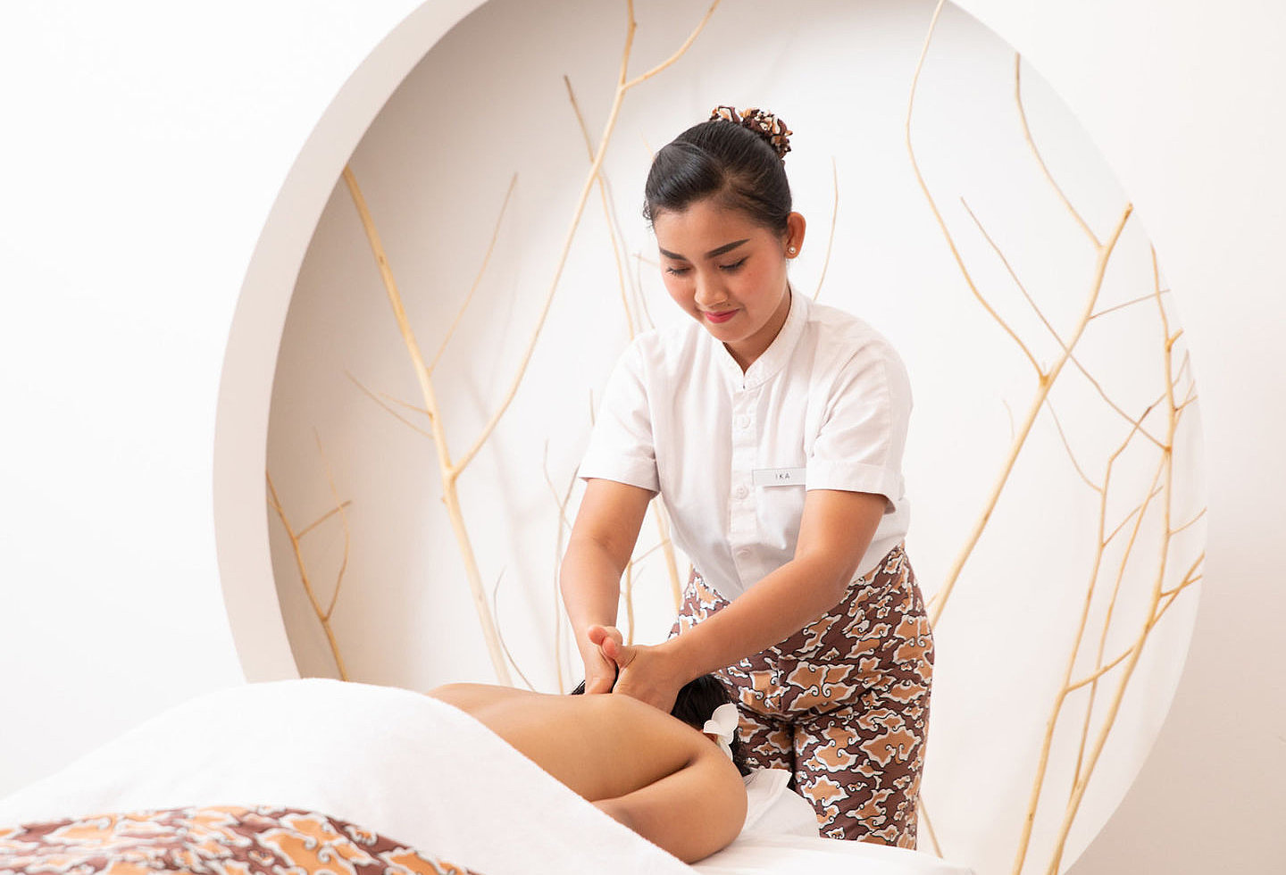Frau bekommt von Dame in Dienstkleidung eine angenehme Rückenmassage.