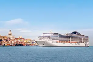Weißes Kreuzfahrtschiff der MSC legt an einer kleinen Küstenstadt am Hafen an.