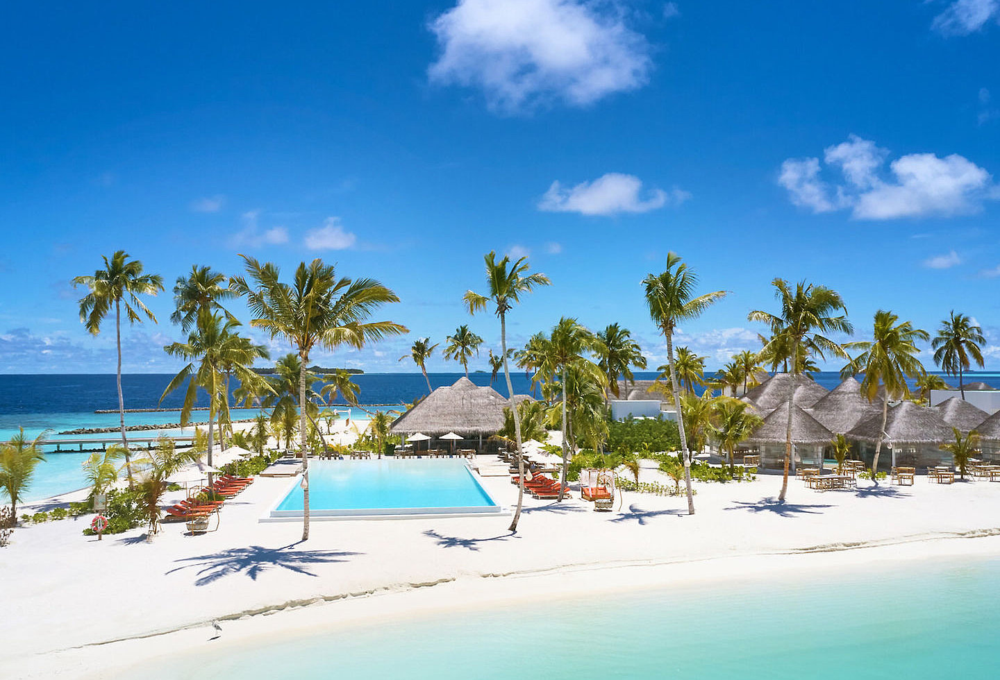 Blick auf den Strand mit Palmen und einem großen Pool