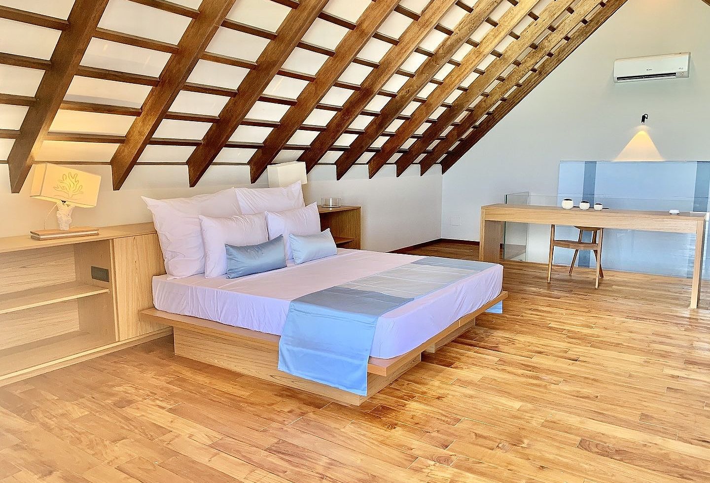 Blick in einen Wohnbereich auf Holzboden, mit einem Doppelbett und Tisch.