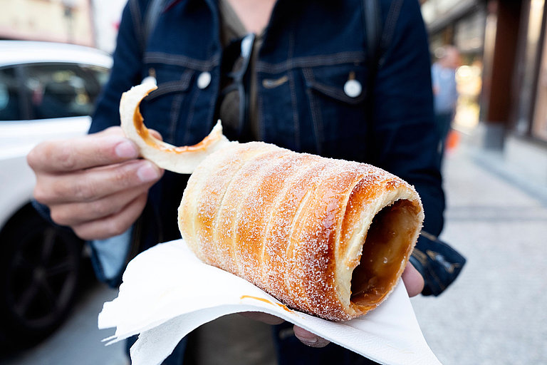 Frisch gebackener Baumkuchen mit Zimt und Zucker auf Papier in der Hand.