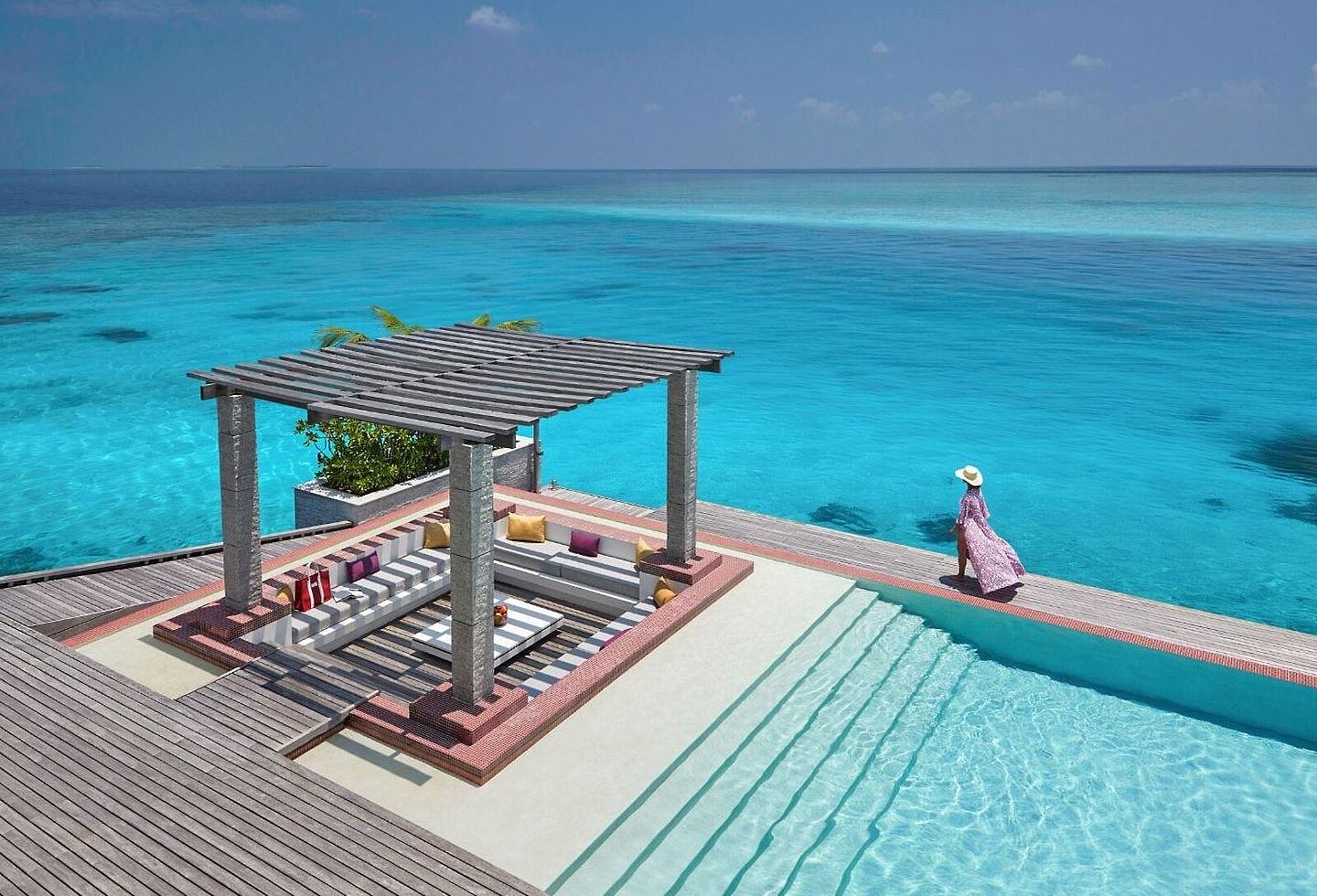 Blick auf Poolbereich direkt am Meer, Holzterrasse und Pavillon mit gemütlichem Sitzbereich.