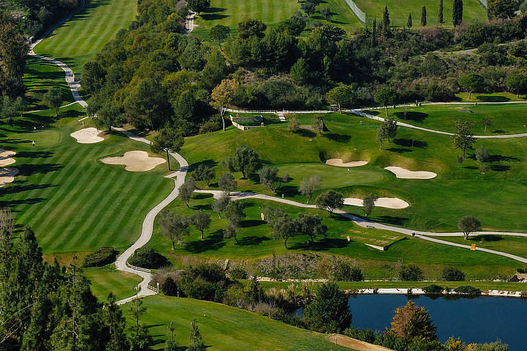 Luftaufnahme eines Golfplatzes in Marbella mit Fairways, Bunkern und Wasser.