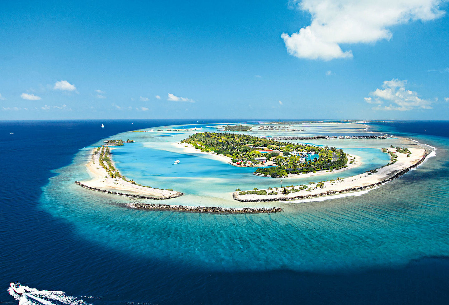 Luftaufnahme des Resorts mit Villen, umgeben von türkisfarbenem Ozean.
