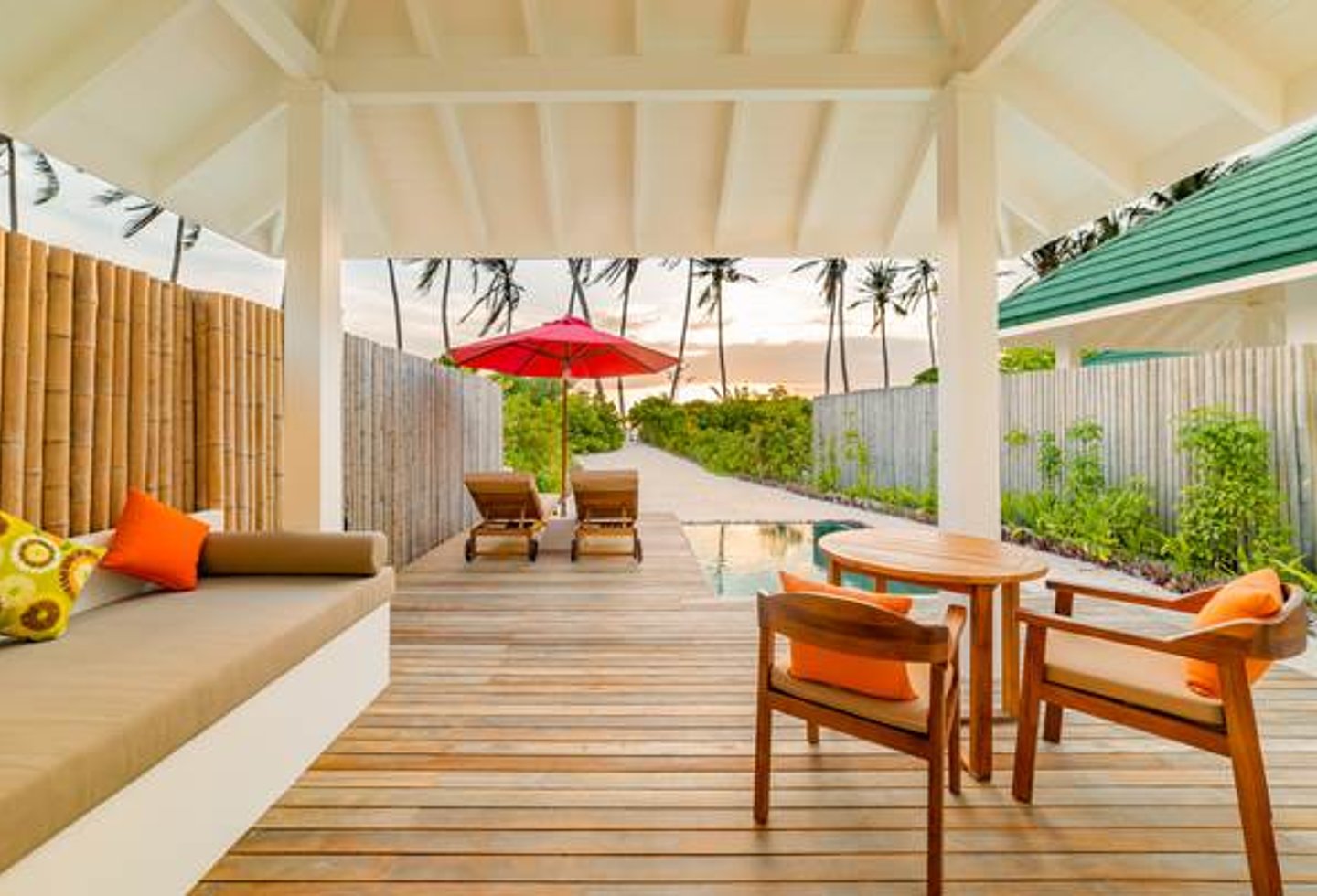 großzügige Holzterrasse mit Couch, Essbereich, Liegen und Pool, Weg zum Strand zwischen Gebüsch