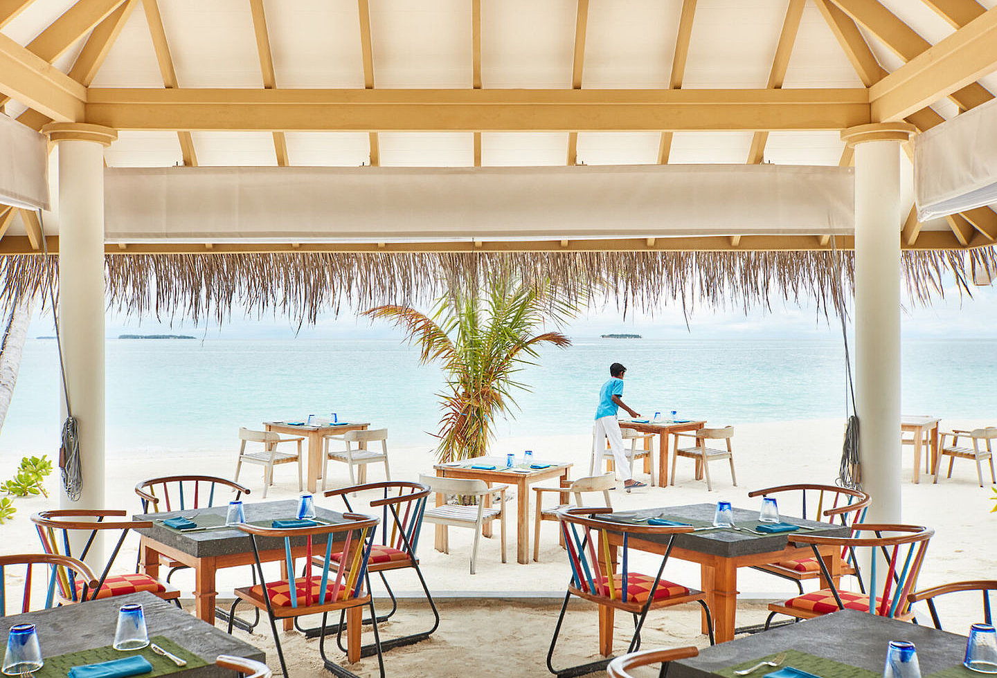 Große Restaurantterasse am Strand unter einem Holzpavillon