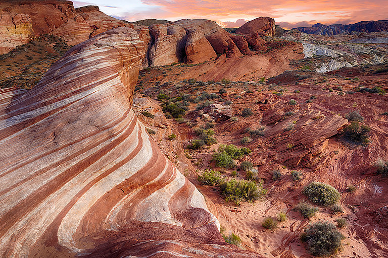 Rote Felslandschaft mit Canyon, trockener Vegetation und weitem Blick.