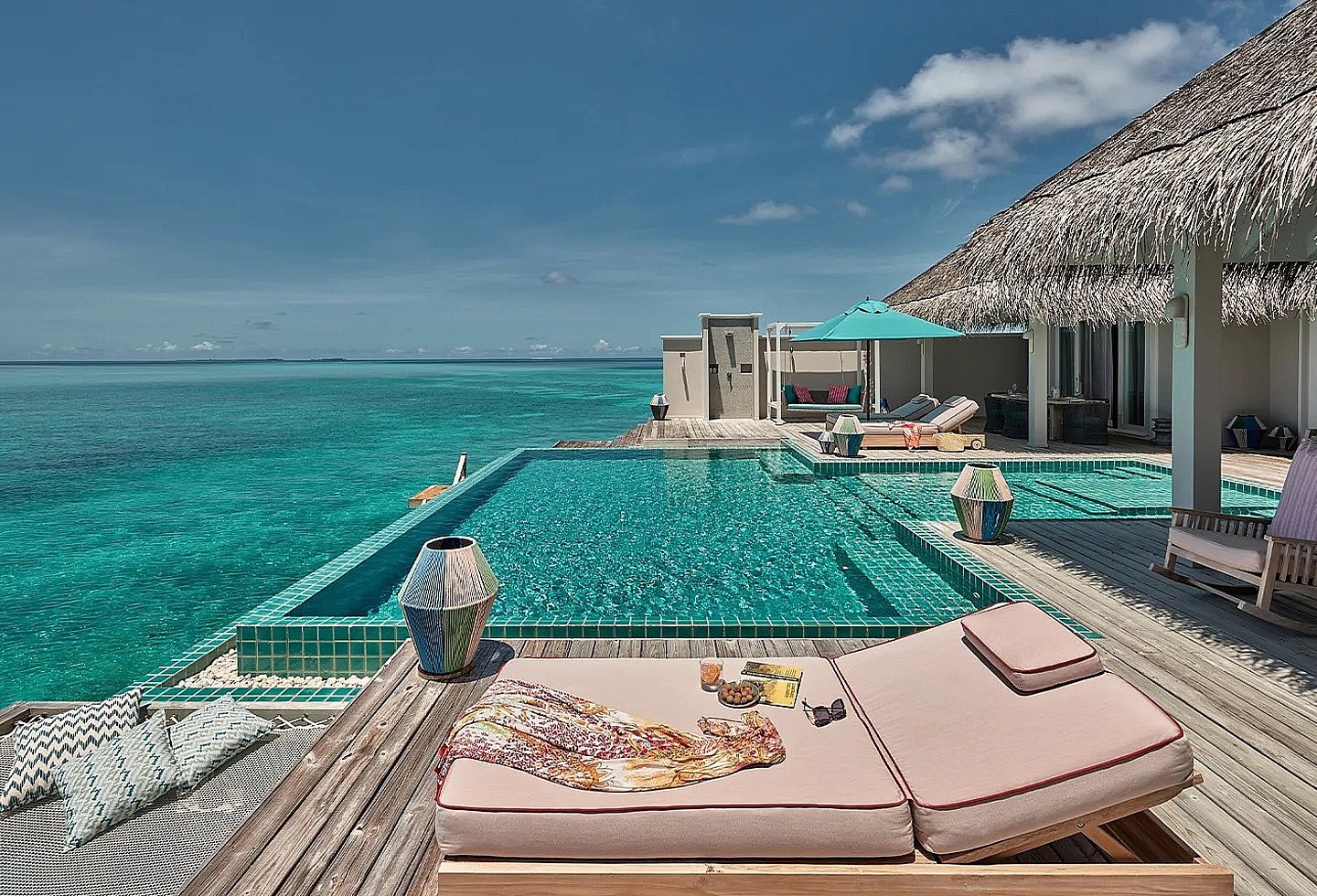 Blick auf den Balkon einer Wasservilla mit privatem Pool und Sonnenliegen.