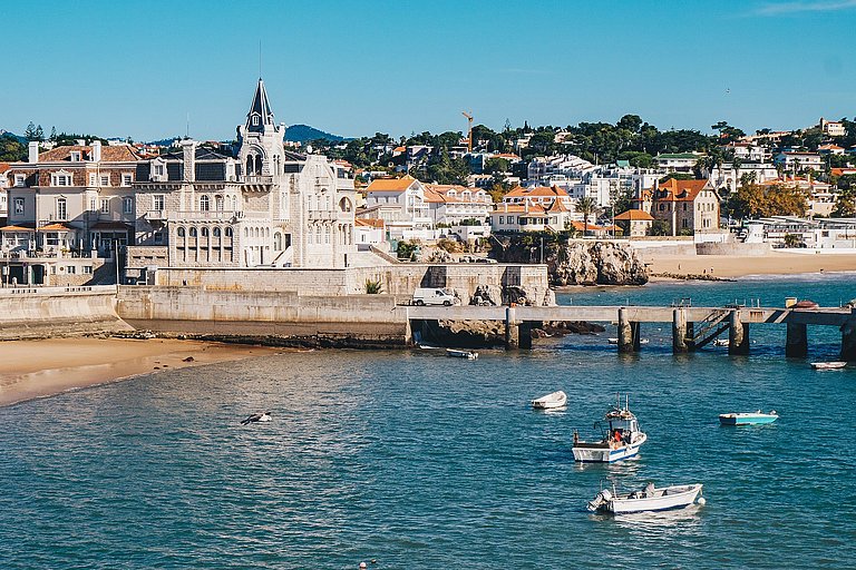 Küstenstadt mit hellem Sandstrand, türkisblauem Meer und Boot vor Portugal.