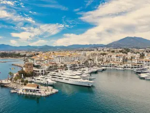 Yachthafen Puerto Banus in Marbella mit weißen Booten, Altstadt und Bergen.