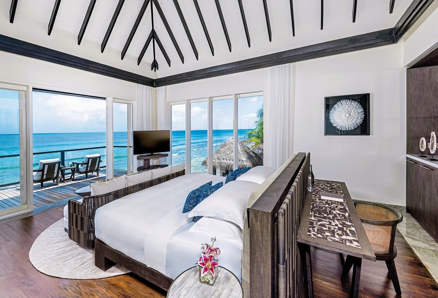 Helles Schlafzimmer mit rundem Bett, Meerblick und großen Fenstern zur Lagune.
