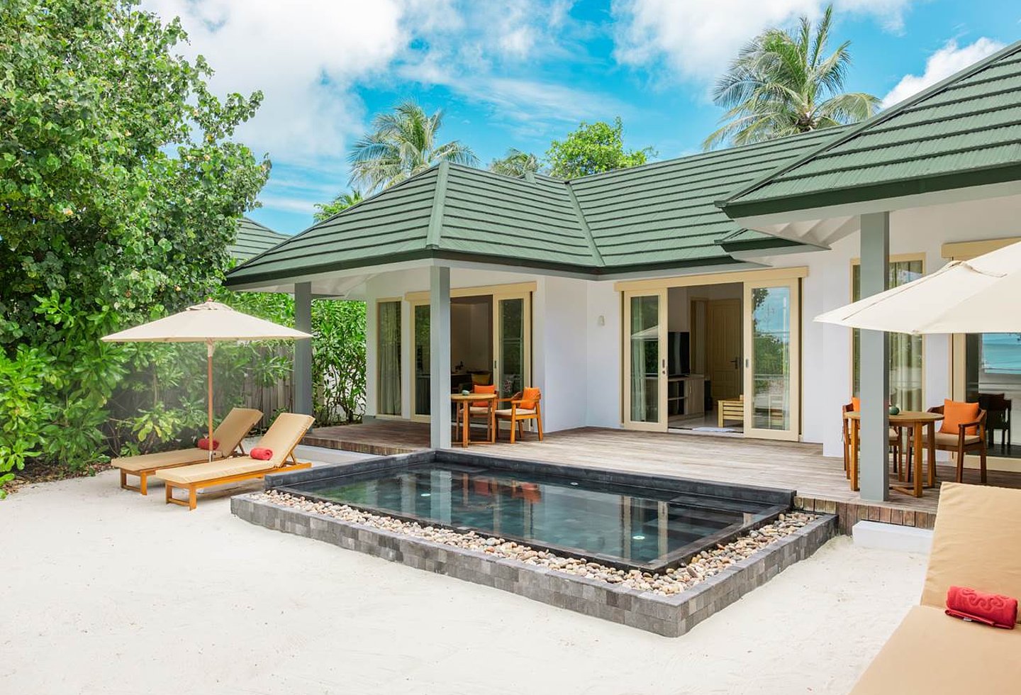 Außenansicht weiße Strandvilla, schwarz eingefasster Pool, 4 Liegen, 2 extra Essbereiche auf der Terrasse