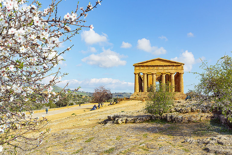 Antiker Tempel im Tal der Tempel mit Blüten, Bäumen und blauem Himmel.