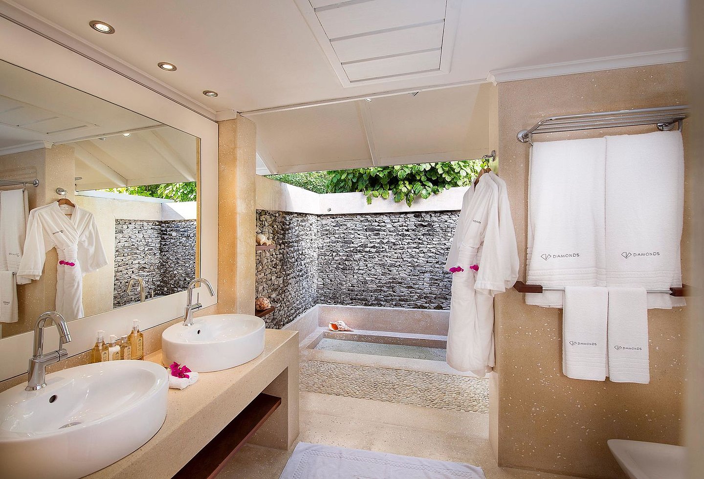 Modernes Badezimmer mit Steinarchitektur und offener Outdoordusche.