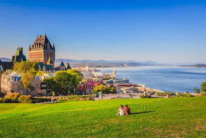 Québec City mit Cháteau Frontenac, grüner Uferpromenade und Blick auf den Fluss.