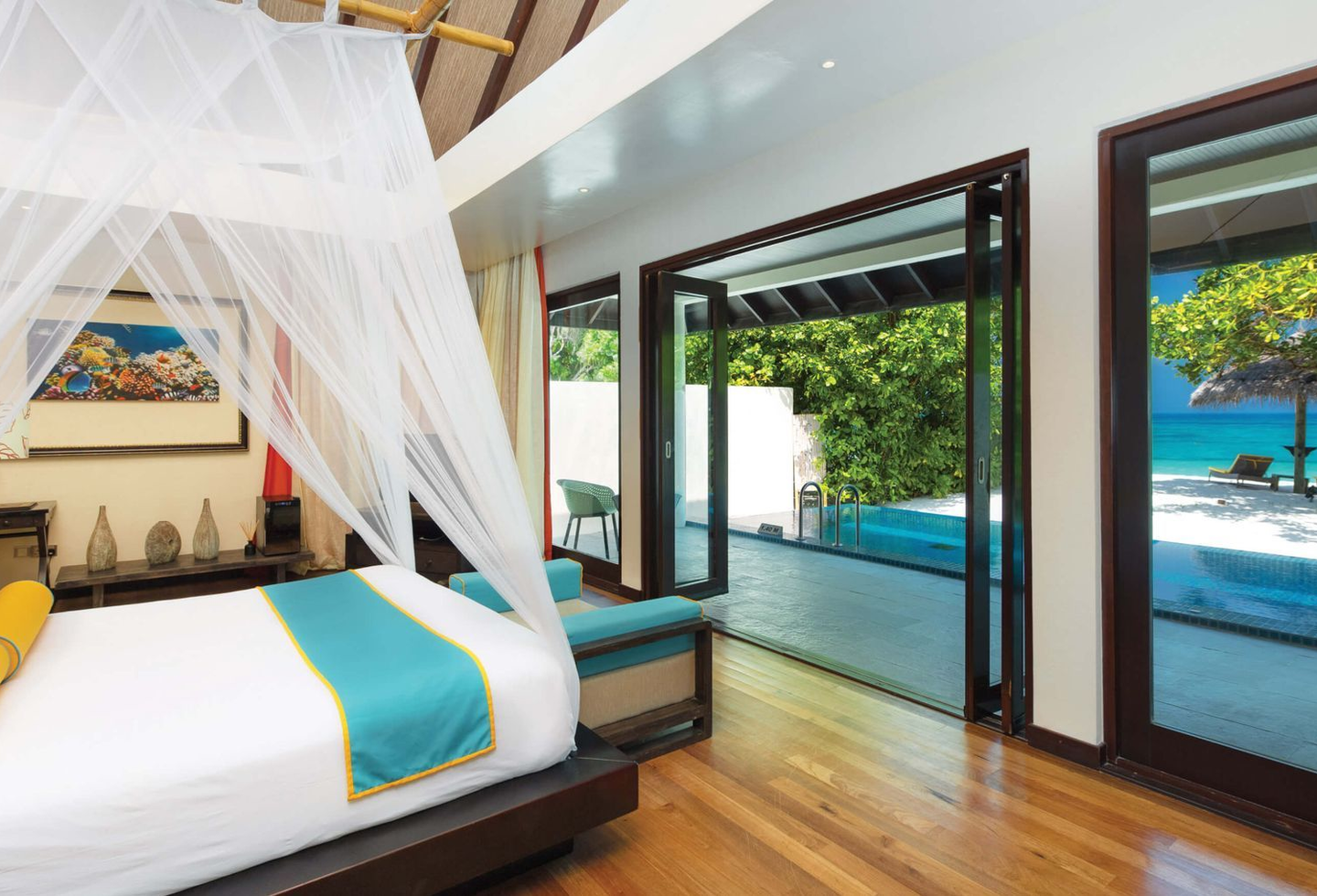 Helles Schlafzimmer mit Himmelbett und großen Glasfronten zum privaten Pool.