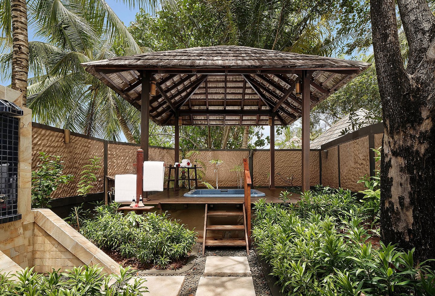 Spa-Bereich im Garten mit Natursteinwegen und tropischer Vegetation.
