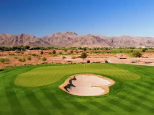 Grüner Golfplatz mit Sandbunker vor kargen Bergen und blauem Himmel in Arizona