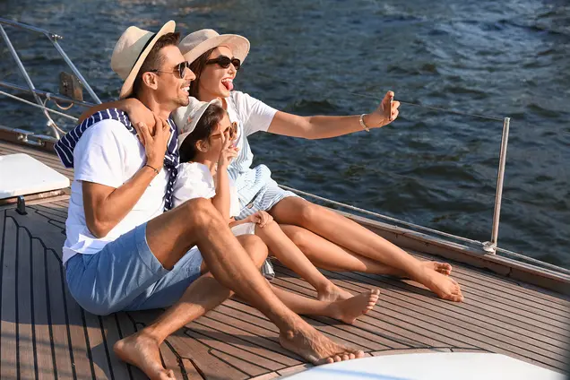 Auf diesem Bild sitzt eine Familie mit Sonnenhüten auf dem Deck eines Bootes.