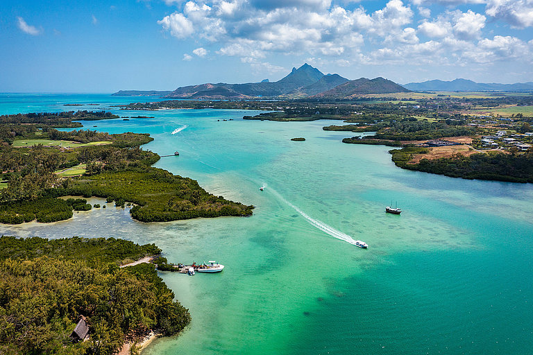 Luftaufnahme einer türkisblauen Bucht auf Mauritius mit Küste und Ortschaft.