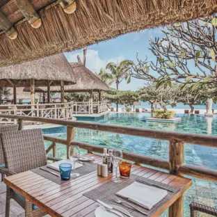 Überdachte Restaurantterrasse mit Meerblick, Holztisch und rustikalem Dach.