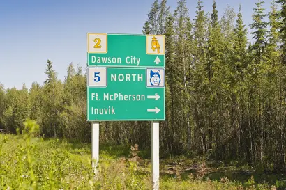 Grünes Straßenschild, vor grüner Landschaft in Yukon, Kanada.