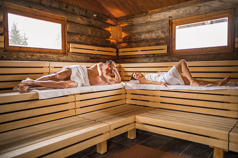 Zwei Personen liegen in einer großen Sauna auf Holt mit schönem Ausblick.