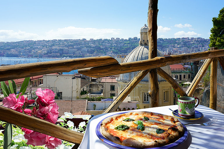 Terrasse mit Pizza, Meerblick, bunten Blumen und Küstenpanorama im Süden.