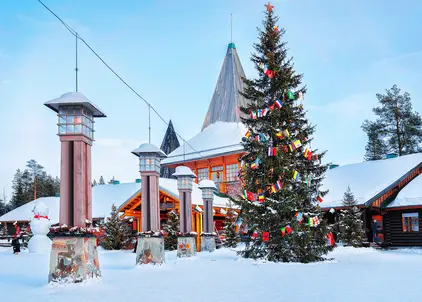 Weihnachtsbaum und festlich beleuchtete Gebäude im Weihnachtsmanndorf in Lappland.
