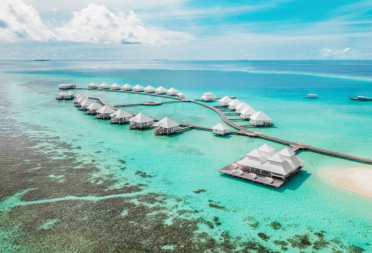 Blick auf die Wasservillen des Ananea Diamonds Athuruga Resorts und das blaue Wasser.