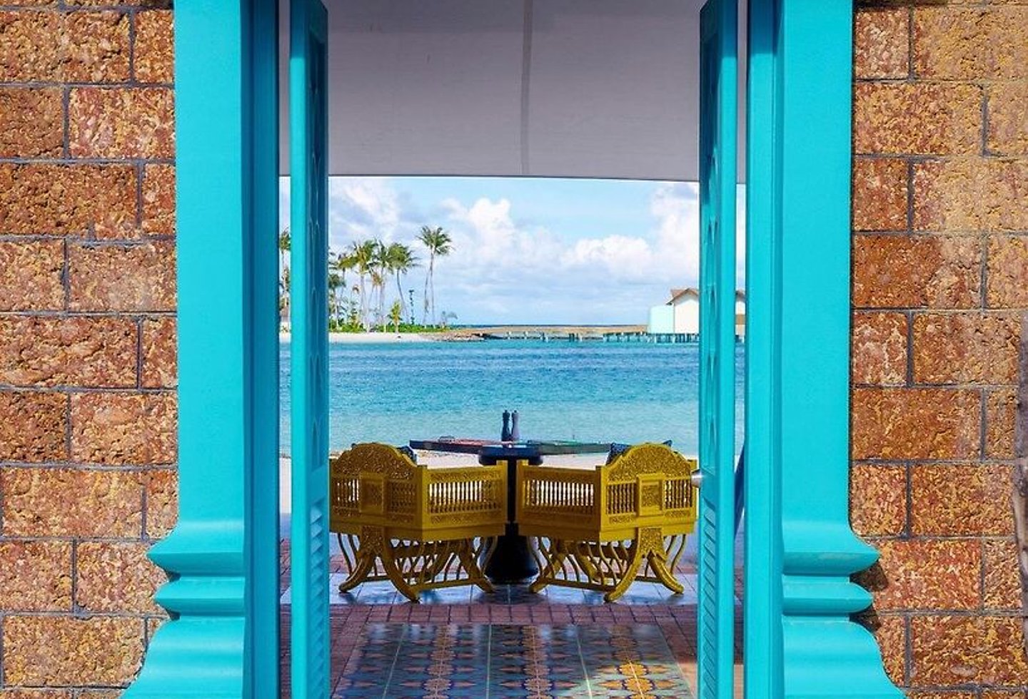 Türkisfarbener Türrahmen, die über eine Terrasse zum Meer führt