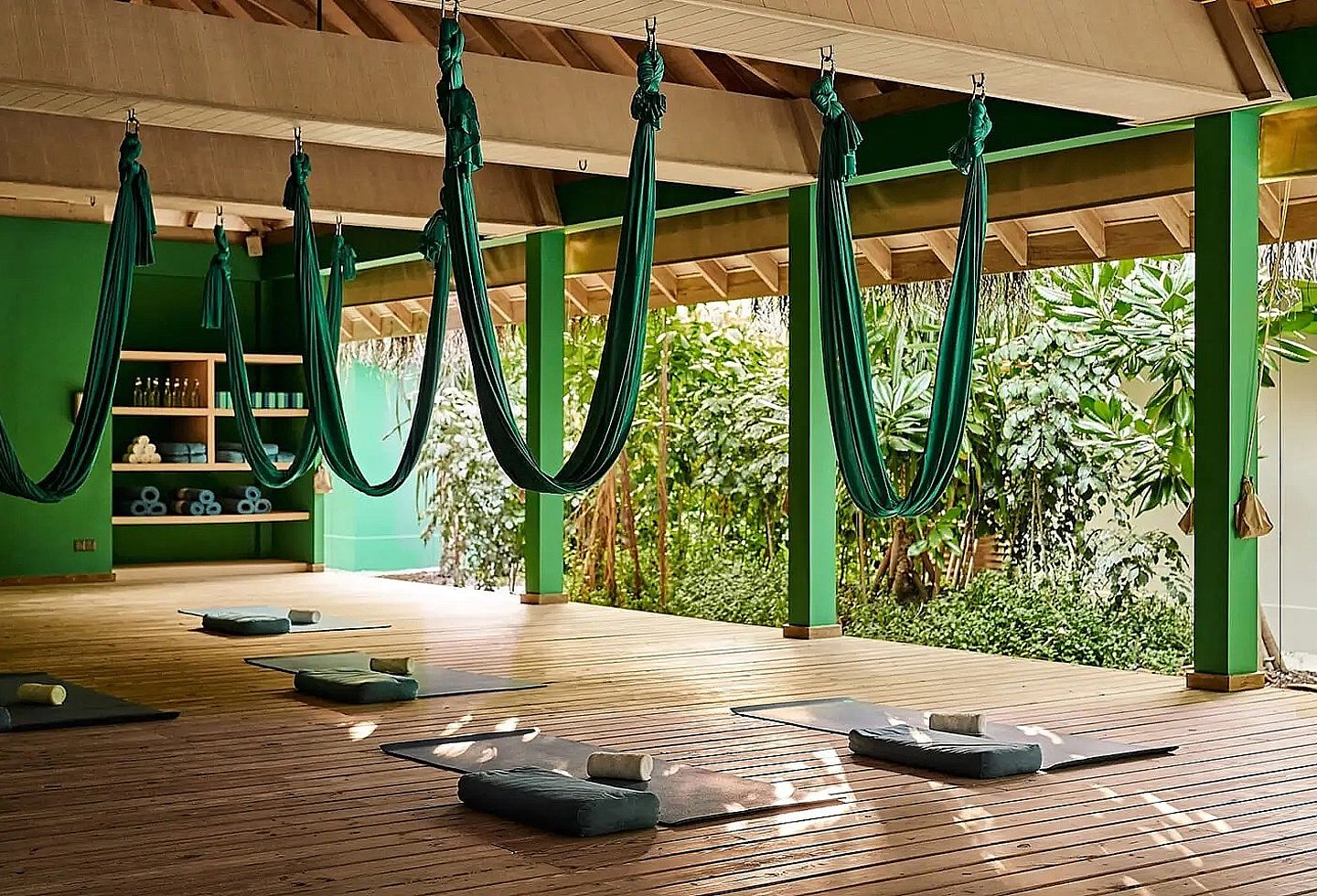 Offener Spa-Bereich mit grünen Seilen von der Wand hängend und Blick auf die Natur.