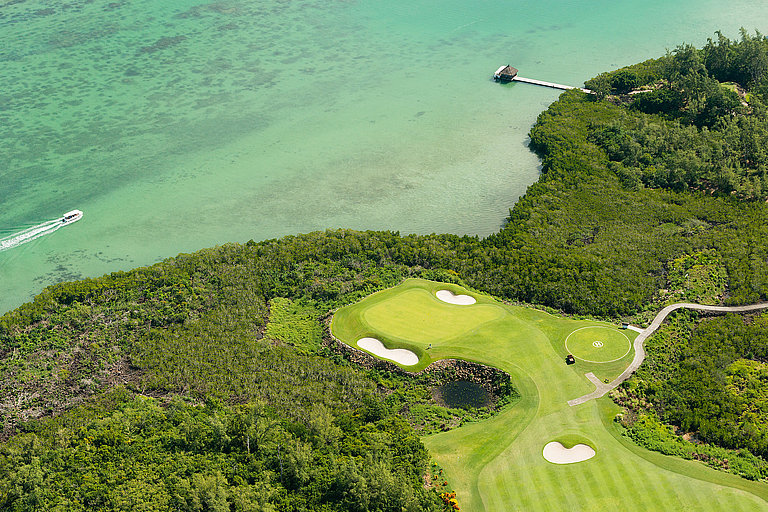 Panoramablick auf einen kleinen Teil eines Golfplatzes und das türkise Meer.