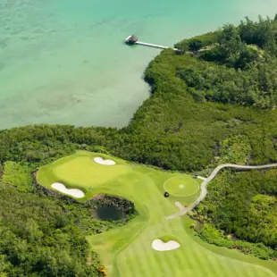 Panoramablick auf einen kleinen Teil eines Golfplatzes und das türkise Meer.