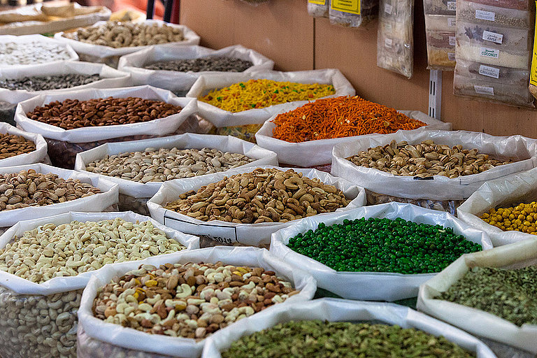 Gewürze und getrocknete Zutaten in Säcken auf einem Marktstand im Freien ausgelegt.