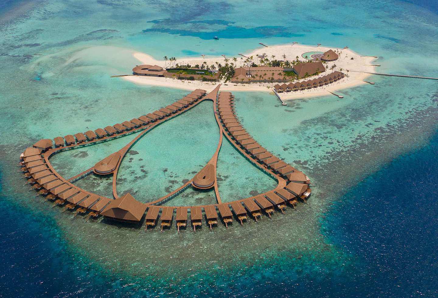 Das Bild zeigt eine kleine Insel und viele Wasservillen durch einen Steg verbunden.